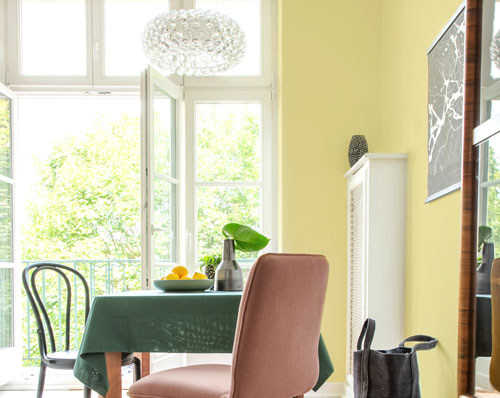 Yellow-green dining room natural wood floors light pink chair